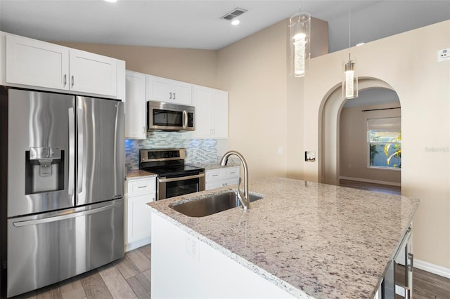 kitchen with a sink, visible vents, vaulted ceiling, appliances with stainless steel finishes, and light wood finished floors