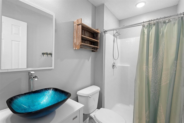 bathroom with toilet, curtained shower, a textured wall, and vanity