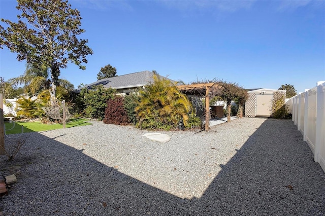 view of yard with an outbuilding, a shed, a patio area, and a fenced backyard