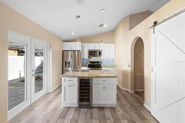 kitchen with wine cooler, stainless steel appliances, lofted ceiling, tasteful backsplash, and visible vents