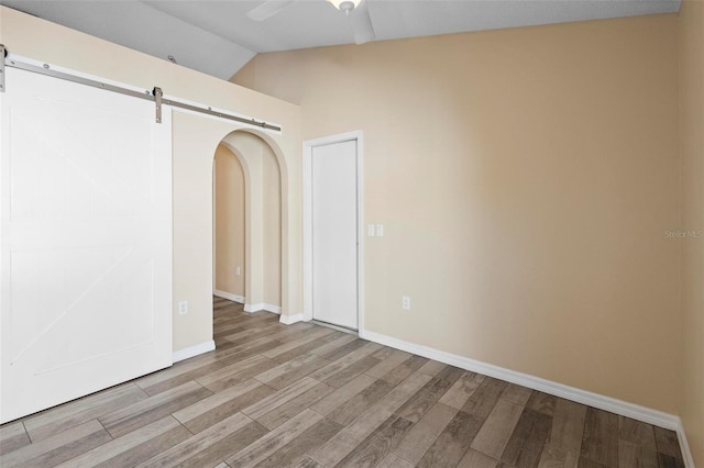 empty room with light wood-style floors, lofted ceiling, ceiling fan, and baseboards