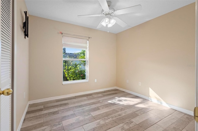 empty room with ceiling fan, baseboards, and wood finished floors