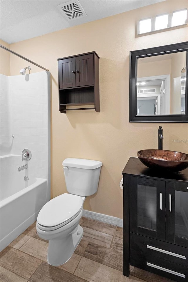 bathroom featuring baseboards, visible vents, toilet, bathtub / shower combination, and vanity