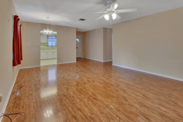 spare room with ceiling fan with notable chandelier, light hardwood / wood-style flooring, and a textured ceiling