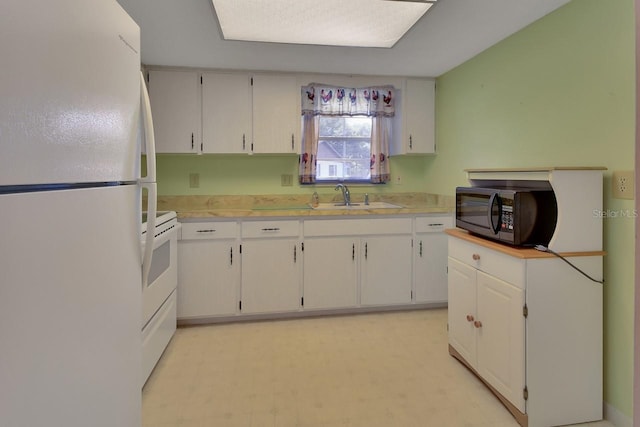 kitchen featuring sink, stove, white fridge, and white cabinets