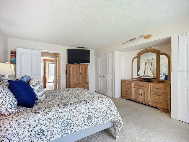 bedroom featuring a textured ceiling and light colored carpet