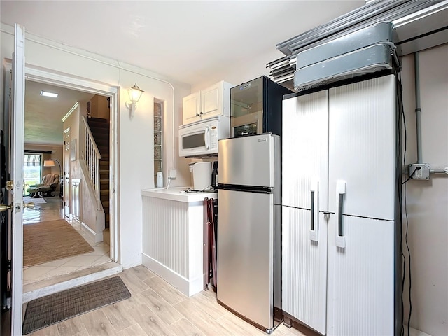 kitchen with white cabinets, white appliances, and light hardwood / wood-style floors