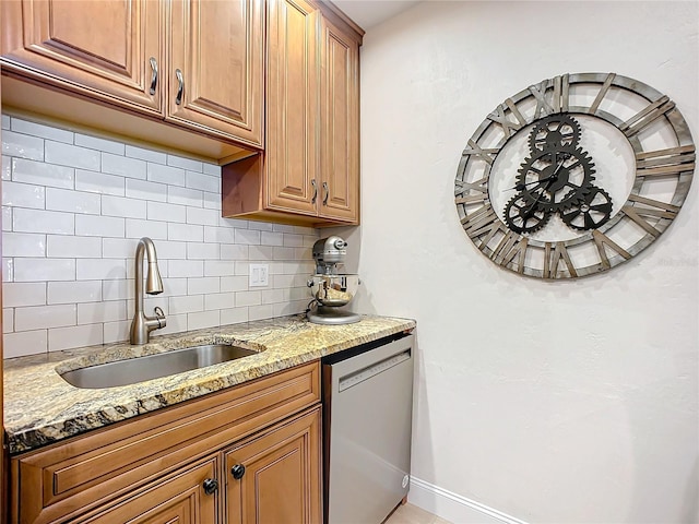 kitchen with dishwasher, light stone counters, sink, and tasteful backsplash