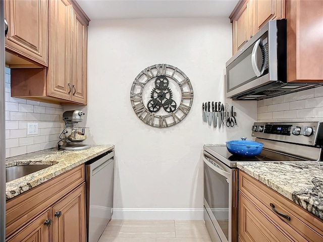 kitchen featuring light stone counters, stainless steel appliances, and decorative backsplash