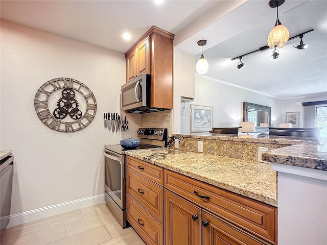 kitchen featuring tasteful backsplash, rail lighting, decorative light fixtures, stainless steel appliances, and light stone counters