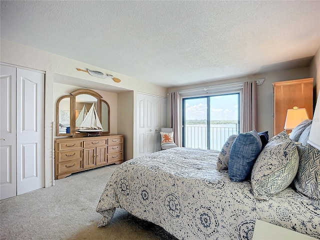 carpeted bedroom with access to exterior, a textured ceiling, and multiple closets