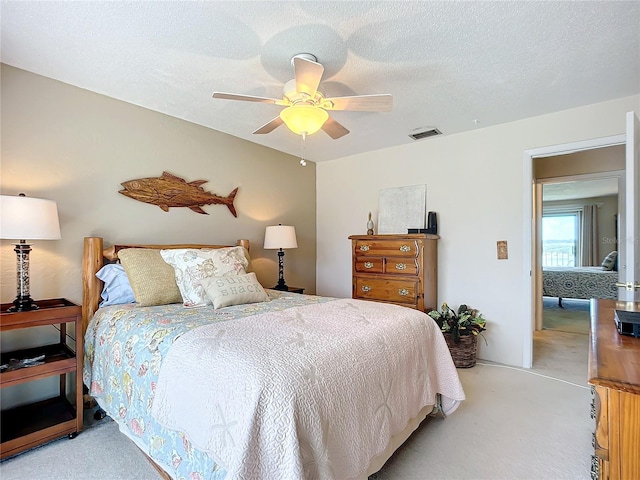 carpeted bedroom featuring a textured ceiling and ceiling fan