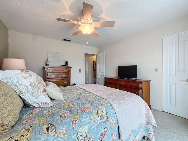 carpeted bedroom featuring a textured ceiling, ceiling fan, and a closet