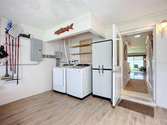 washroom with electric panel, light hardwood / wood-style floors, and independent washer and dryer