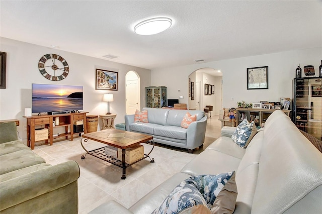 living area with arched walkways, light tile patterned flooring, and visible vents