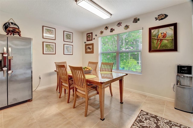 dining room with a textured ceiling, light tile patterned floors, and baseboards