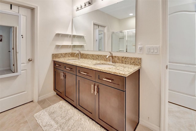 bathroom featuring tile patterned flooring, a sink, a shower stall, and double vanity