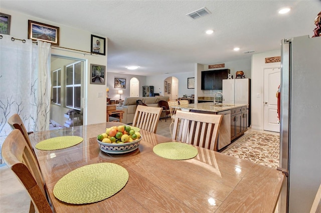 dining area with arched walkways, light tile patterned floors, recessed lighting, visible vents, and a textured ceiling