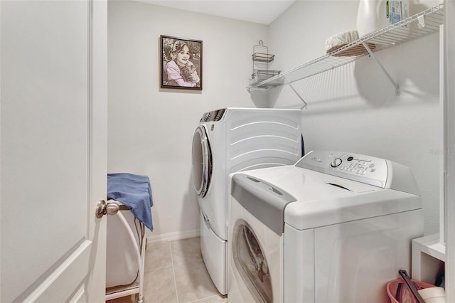 laundry room featuring laundry area, washer and clothes dryer, baseboards, and light tile patterned floors