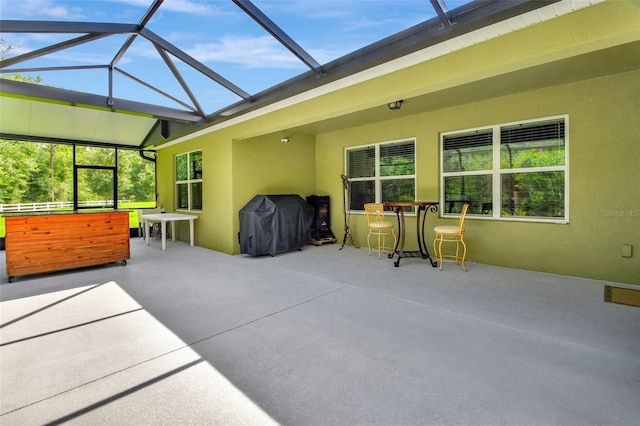 view of patio featuring glass enclosure and a grill