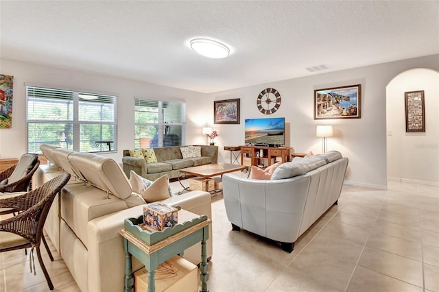 living area with visible vents, a textured ceiling, baseboards, and light tile patterned flooring