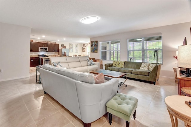 living room with light tile patterned floors, baseboards, a textured ceiling, and recessed lighting