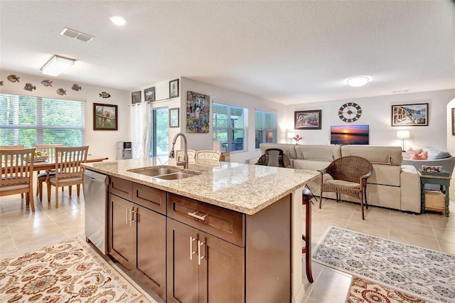 kitchen featuring light tile patterned floors, visible vents, open floor plan, a sink, and dishwasher