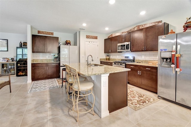 kitchen featuring light tile patterned floors, stainless steel appliances, a sink, and dark brown cabinetry