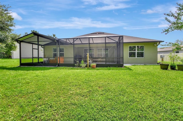 rear view of house featuring glass enclosure, a lawn, and stucco siding