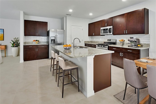 317 Nowell Loop, Deland, FL 32724 - kitchen with appliances with stainless steel finishes, a sink, tasteful backsplash, a kitchen bar, and light tile patterned floors