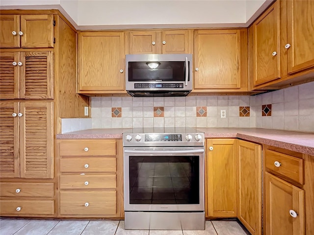 kitchen featuring light tile patterned flooring, stainless steel appliances, and tasteful backsplash