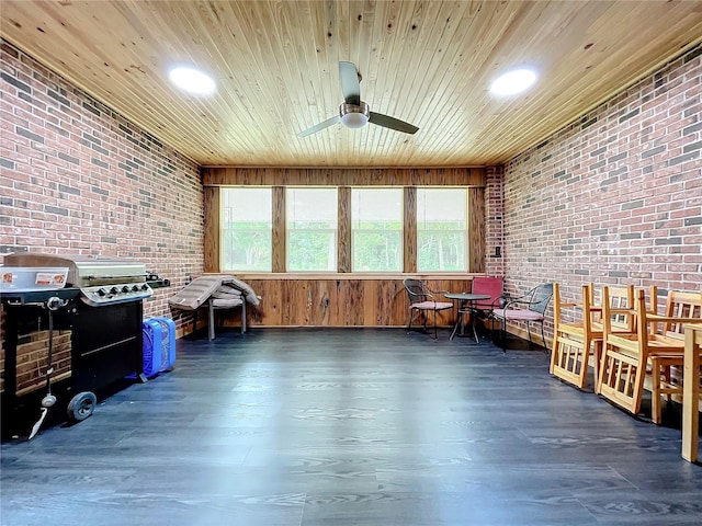 miscellaneous room with ceiling fan, brick wall, dark wood-type flooring, and wooden ceiling