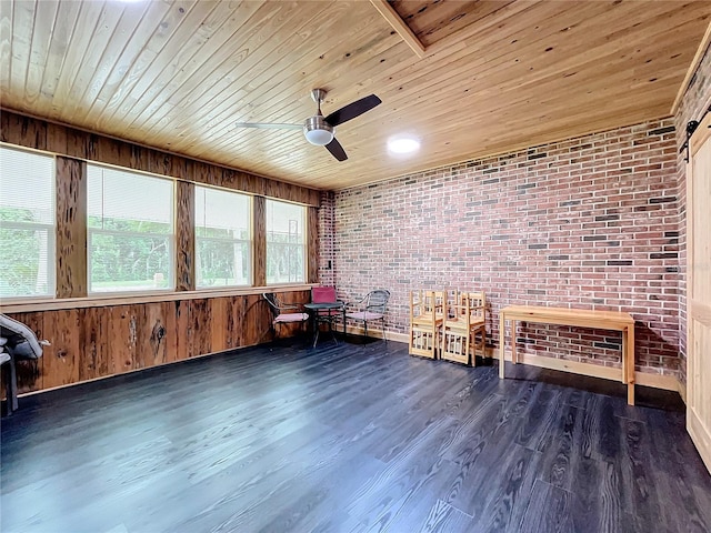 unfurnished room featuring ceiling fan, brick wall, dark hardwood / wood-style flooring, wood ceiling, and a barn door