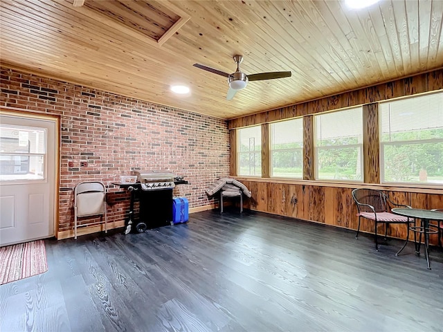 misc room with wood walls, dark wood-type flooring, ceiling fan, wood ceiling, and brick wall