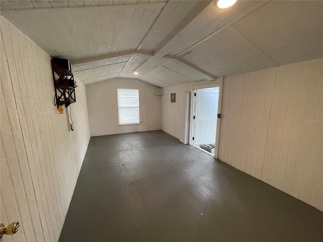 bonus room with wooden walls and vaulted ceiling