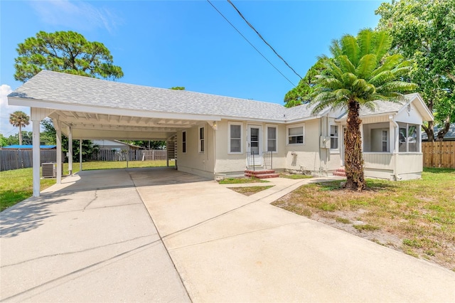 ranch-style home with a front lawn, central air condition unit, and a carport