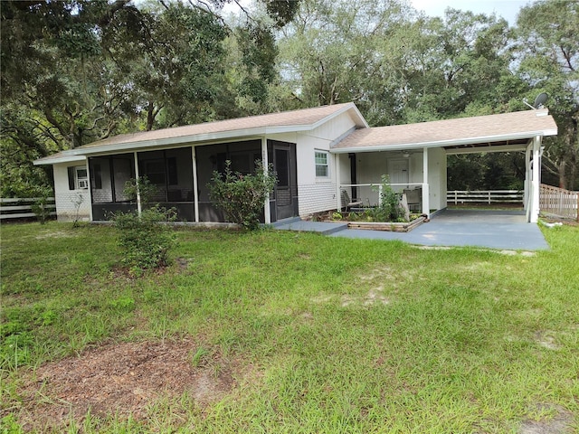 view of front of house with a carport, a front lawn, and a sunroom