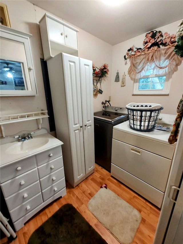 laundry room with light wood-type flooring, sink, and washing machine and clothes dryer