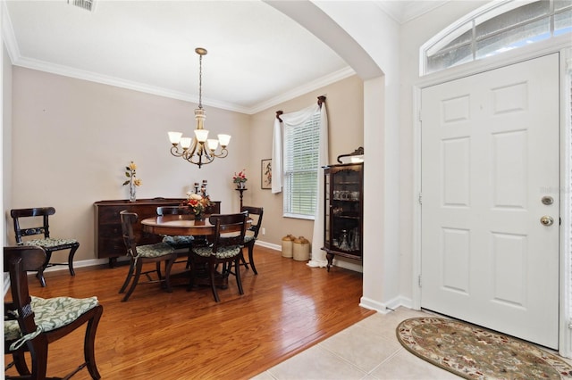 dining room with crown molding, light hardwood / wood-style floors, and an inviting chandelier