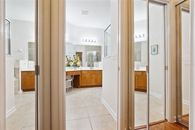 bathroom with tile patterned floors, a shower with door, and vanity