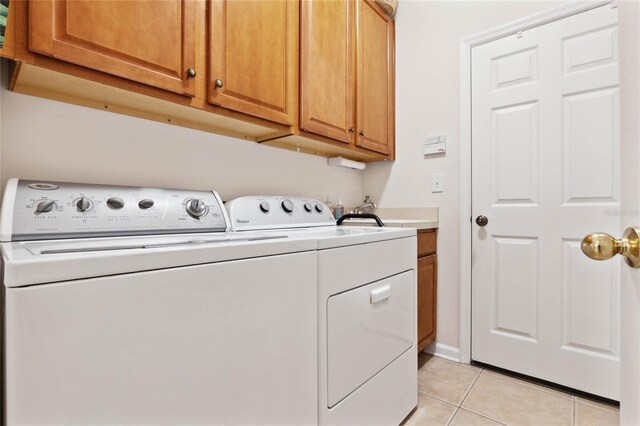 laundry room featuring light tile patterned floors, washing machine and dryer, and cabinets