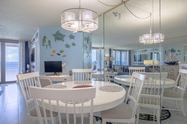 dining room featuring a textured ceiling, plenty of natural light, an inviting chandelier, and tile patterned flooring