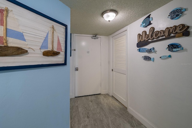 corridor with light hardwood / wood-style floors and a textured ceiling