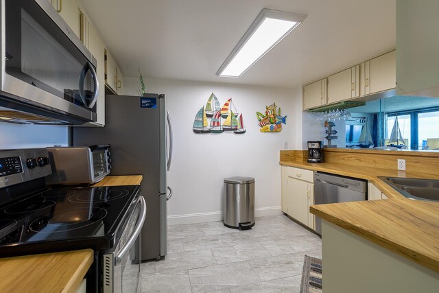 kitchen featuring stainless steel appliances, sink, and cream cabinetry