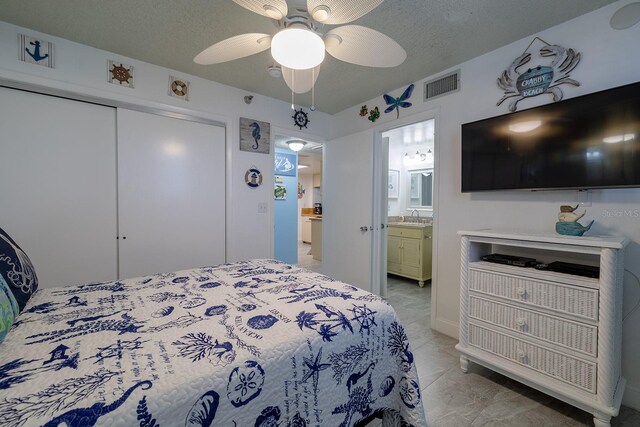 bedroom featuring a textured ceiling, a closet, ceiling fan, and ensuite bath