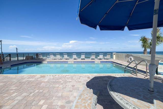 view of swimming pool with a water view and a patio