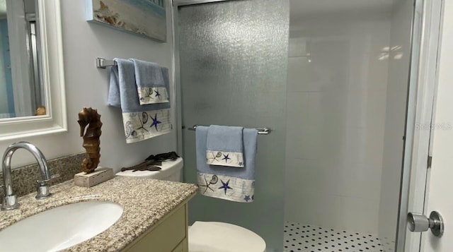 bathroom with tiled shower, vanity, and toilet