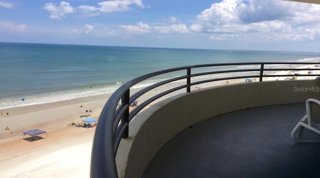 balcony featuring a view of the beach and a water view