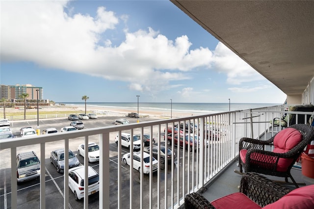 balcony featuring a view of the beach and a water view