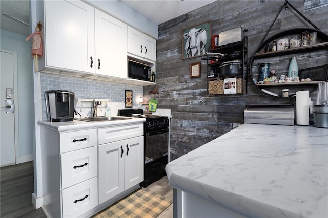 kitchen featuring black appliances, wood-type flooring, backsplash, sink, and white cabinetry